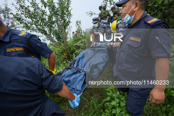 Nepali security forces are carrying the bodies of victims to the hearse from the site of the crashed Air Dynasty Helicopter in Nuwakot Distr...