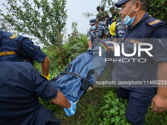 Nepali security forces are carrying the bodies of victims to the hearse from the site of the crashed Air Dynasty Helicopter in Nuwakot Distr...