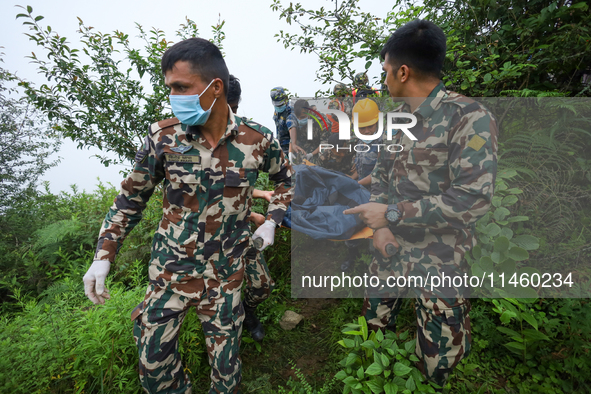 Nepali security forces are carrying the bodies of victims to the hearse from the site of the crashed Air Dynasty Helicopter in Nuwakot Distr...