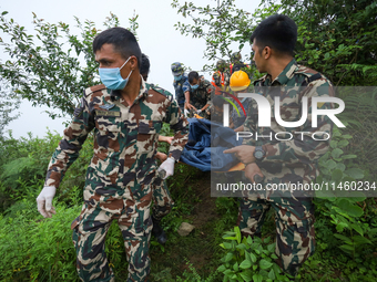 Nepali security forces are carrying the bodies of victims to the hearse from the site of the crashed Air Dynasty Helicopter in Nuwakot Distr...