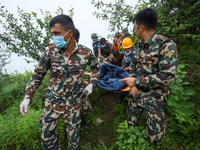 Nepali security forces are carrying the bodies of victims to the hearse from the site of the crashed Air Dynasty Helicopter in Nuwakot Distr...