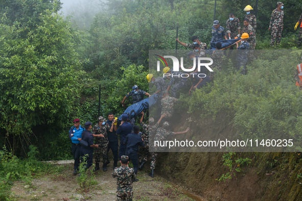 Nepali security forces are carrying the bodies of victims to the hearse from the site of the crashed Air Dynasty Helicopter in Nuwakot Distr...