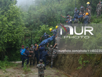 Nepali security forces are carrying the bodies of victims to the hearse from the site of the crashed Air Dynasty Helicopter in Nuwakot Distr...