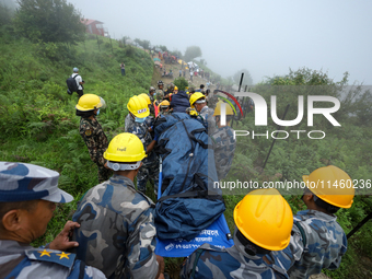 Nepali security forces are carrying the bodies of victims to the hearse from the site of the crashed Air Dynasty Helicopter in Nuwakot Distr...