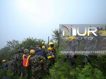 Nepali security forces are carrying the bodies of victims to the hearse from the site of the crashed Air Dynasty Helicopter in Nuwakot Distr...