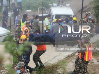 Nepali security forces are carrying the bodies of victims to the hearse from the site of the crashed Air Dynasty Helicopter in Nuwakot Distr...