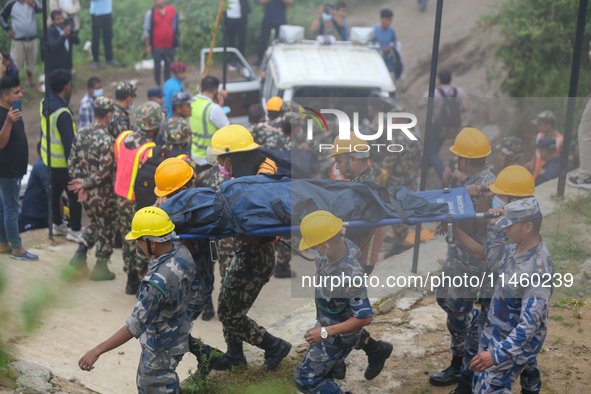 Nepali security forces are carrying the bodies of victims to the hearse from the site of the crashed Air Dynasty Helicopter in Nuwakot Distr...