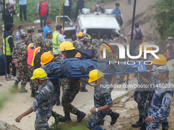 Nepali security forces are carrying the bodies of victims to the hearse from the site of the crashed Air Dynasty Helicopter in Nuwakot Distr...