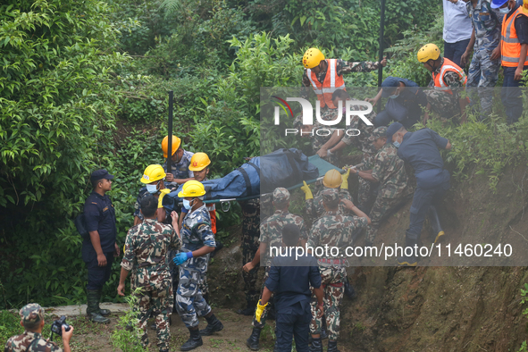 Nepali security forces are carrying the bodies of victims to the hearse from the site of the crashed Air Dynasty Helicopter in Nuwakot Distr...