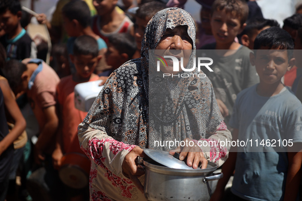 Displaced Palestinians are gathering to receive food cooked by a charity kitchen, amid food scarcity, as the Israel-Hamas conflict continues...