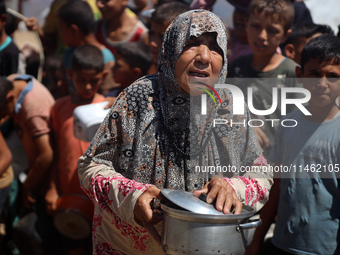 Displaced Palestinians are gathering to receive food cooked by a charity kitchen, amid food scarcity, as the Israel-Hamas conflict continues...