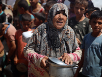 Displaced Palestinians are gathering to receive food cooked by a charity kitchen, amid food scarcity, as the Israel-Hamas conflict continues...