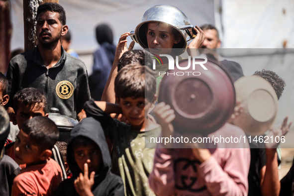 Displaced Palestinians are gathering to receive food cooked by a charity kitchen, amid food scarcity, as the Israel-Hamas conflict continues...