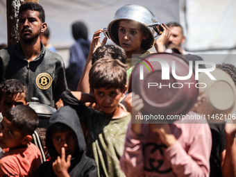 Displaced Palestinians are gathering to receive food cooked by a charity kitchen, amid food scarcity, as the Israel-Hamas conflict continues...