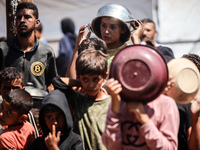 Displaced Palestinians are gathering to receive food cooked by a charity kitchen, amid food scarcity, as the Israel-Hamas conflict continues...