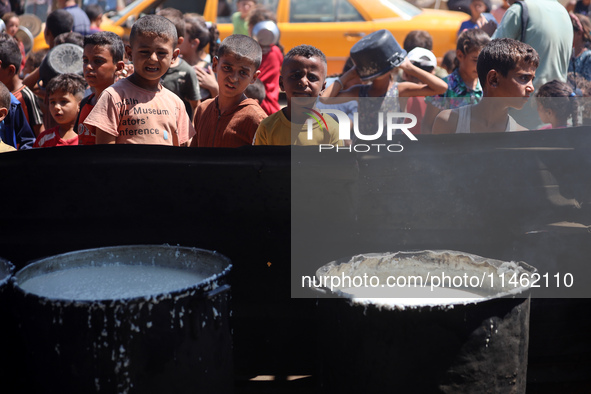 Displaced Palestinians are gathering to receive food cooked by a charity kitchen, amid food scarcity, as the Israel-Hamas conflict continues...