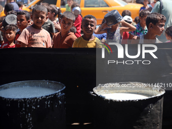 Displaced Palestinians are gathering to receive food cooked by a charity kitchen, amid food scarcity, as the Israel-Hamas conflict continues...