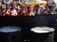 Displaced Palestinians are gathering to receive food cooked by a charity kitchen, amid food scarcity, as the Israel-Hamas conflict continues...