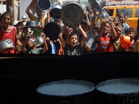 Displaced Palestinians are gathering to receive food cooked by a charity kitchen, amid food scarcity, as the Israel-Hamas conflict continues...