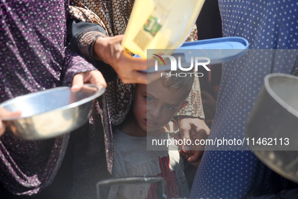 Displaced Palestinians are gathering to receive food cooked by a charity kitchen, amid food scarcity, as the Israel-Hamas conflict continues...