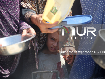 Displaced Palestinians are gathering to receive food cooked by a charity kitchen, amid food scarcity, as the Israel-Hamas conflict continues...