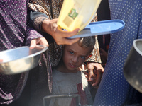 Displaced Palestinians are gathering to receive food cooked by a charity kitchen, amid food scarcity, as the Israel-Hamas conflict continues...