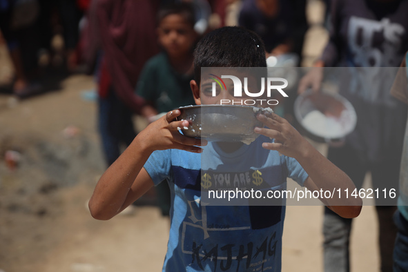 A Palestinian is carrying food cooked by a charity kitchen, amid shortages of aid supplies, as the conflict between Israel and Hamas continu...