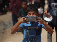 A Palestinian is carrying food cooked by a charity kitchen, amid shortages of aid supplies, as the conflict between Israel and Hamas continu...