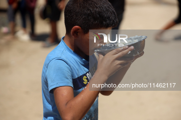 A Palestinian is carrying food cooked by a charity kitchen, amid shortages of aid supplies, as the conflict between Israel and Hamas continu...