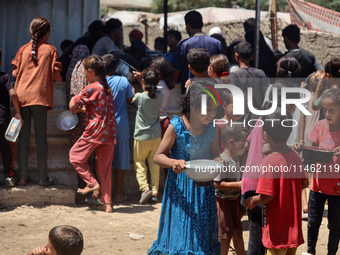 Displaced Palestinians are gathering to receive food cooked by a charity kitchen, amid food scarcity, as the Israel-Hamas conflict continues...