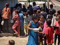 Displaced Palestinians are gathering to receive food cooked by a charity kitchen, amid food scarcity, as the Israel-Hamas conflict continues...