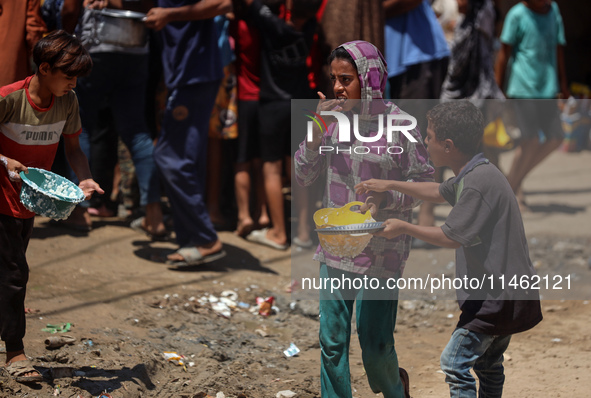 Displaced Palestinians are gathering to receive food cooked by a charity kitchen, amid food scarcity, as the Israel-Hamas conflict continues...