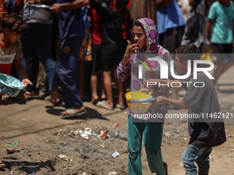 Displaced Palestinians are gathering to receive food cooked by a charity kitchen, amid food scarcity, as the Israel-Hamas conflict continues...