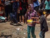 Displaced Palestinians are gathering to receive food cooked by a charity kitchen, amid food scarcity, as the Israel-Hamas conflict continues...