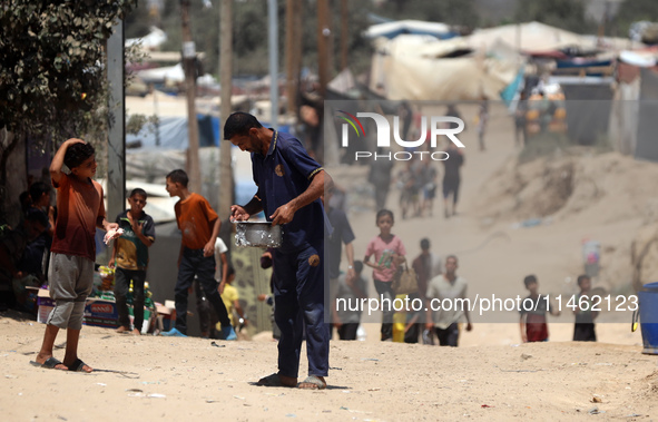 A Palestinian is carrying food cooked by a charity kitchen, amid shortages of aid supplies, as the conflict between Israel and Hamas continu...