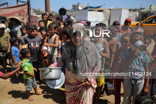 Displaced Palestinians are gathering to receive food cooked by a charity kitchen, amid food scarcity, as the Israel-Hamas conflict continues...