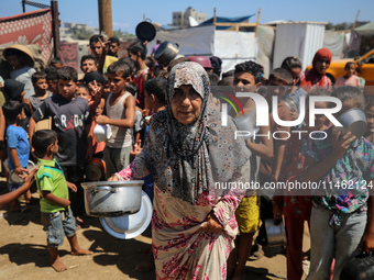 Displaced Palestinians are gathering to receive food cooked by a charity kitchen, amid food scarcity, as the Israel-Hamas conflict continues...