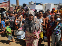 Displaced Palestinians are gathering to receive food cooked by a charity kitchen, amid food scarcity, as the Israel-Hamas conflict continues...