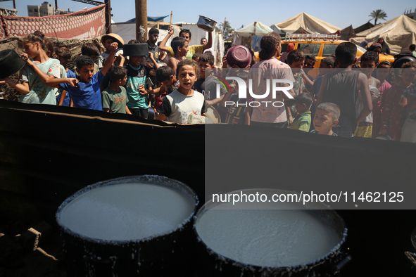 Displaced Palestinians are gathering to receive food cooked by a charity kitchen, amid food scarcity, as the Israel-Hamas conflict continues...