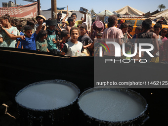 Displaced Palestinians are gathering to receive food cooked by a charity kitchen, amid food scarcity, as the Israel-Hamas conflict continues...