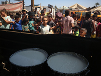 Displaced Palestinians are gathering to receive food cooked by a charity kitchen, amid food scarcity, as the Israel-Hamas conflict continues...