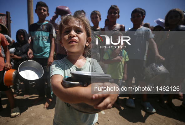 Displaced Palestinians are gathering to receive food cooked by a charity kitchen, amid food scarcity, as the Israel-Hamas conflict continues...