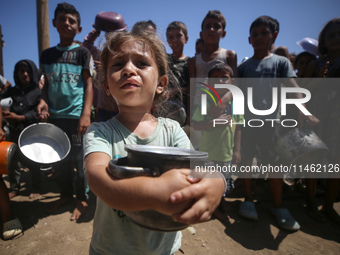 Displaced Palestinians are gathering to receive food cooked by a charity kitchen, amid food scarcity, as the Israel-Hamas conflict continues...