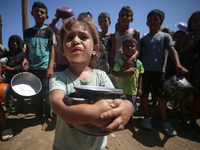 Displaced Palestinians are gathering to receive food cooked by a charity kitchen, amid food scarcity, as the Israel-Hamas conflict continues...