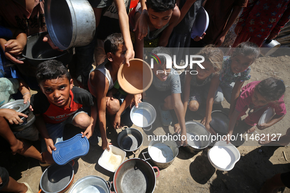 Displaced Palestinians are gathering to receive food cooked by a charity kitchen, amid food scarcity, as the Israel-Hamas conflict continues...