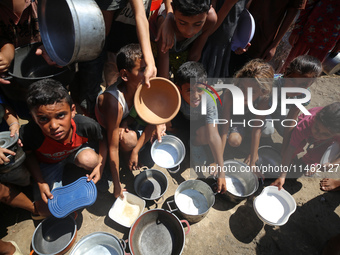 Displaced Palestinians are gathering to receive food cooked by a charity kitchen, amid food scarcity, as the Israel-Hamas conflict continues...