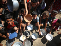 Displaced Palestinians are gathering to receive food cooked by a charity kitchen, amid food scarcity, as the Israel-Hamas conflict continues...