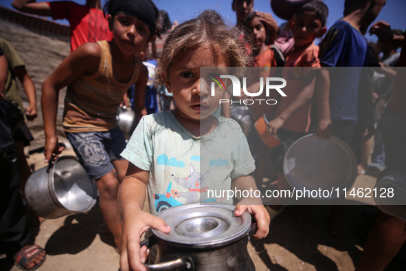 Displaced Palestinians are gathering to receive food cooked by a charity kitchen, amid food scarcity, as the Israel-Hamas conflict continues...