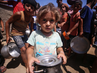 Displaced Palestinians are gathering to receive food cooked by a charity kitchen, amid food scarcity, as the Israel-Hamas conflict continues...