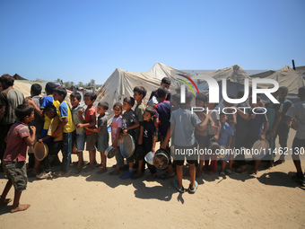 Displaced Palestinians are gathering to receive food cooked by a charity kitchen, amid food scarcity, as the Israel-Hamas conflict continues...